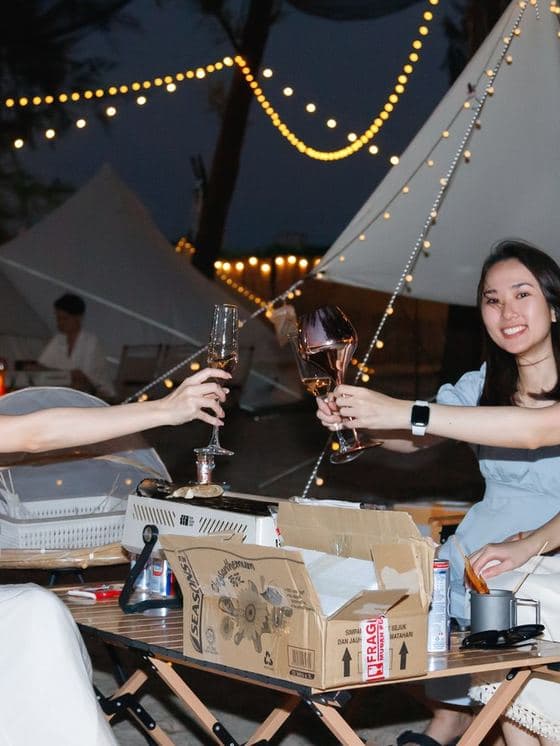 Guests toasting at an outdoor evening setup strung with lights